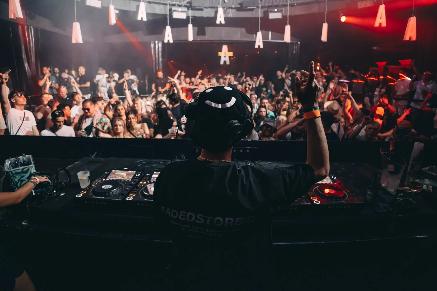 DJ performing at Abode event in Ayia Napa with a packed nightclub crowd dancing under red lights and lively atmosphere