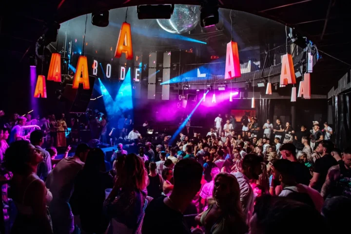 Crowded dance floor at Ibiza Eden club hosting the famous Abode, with vibrant lights and a disco ball, capturing the lively clubbing atmosphere.