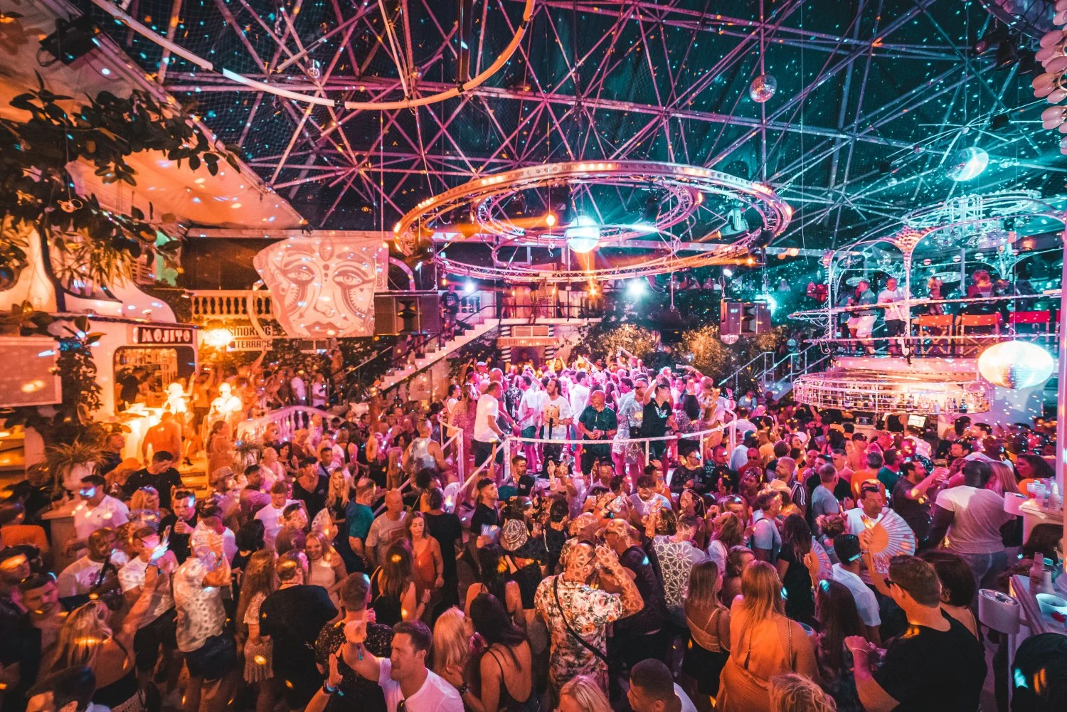 Packed dancefloor at Es Paradis Ibiza, lights flashing, disco balls shining and nonstop summer party energy.