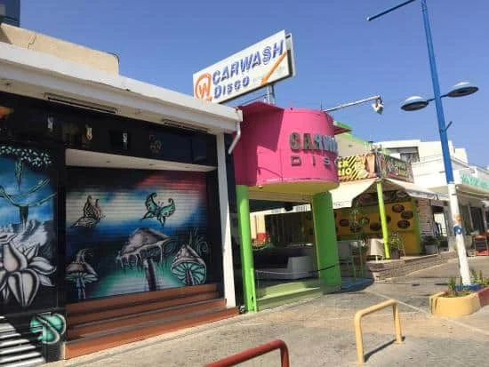 Carwash classic disco style club in Ayia Napa, featuring a vibrant mural and pink-green facade under a clear blue sky.