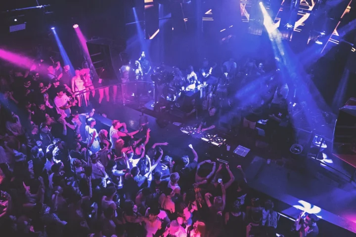 Crowd raving at Eden Club Ibiza with DJ on deck, flashing lights, heavy beats and full-on summer party energy.