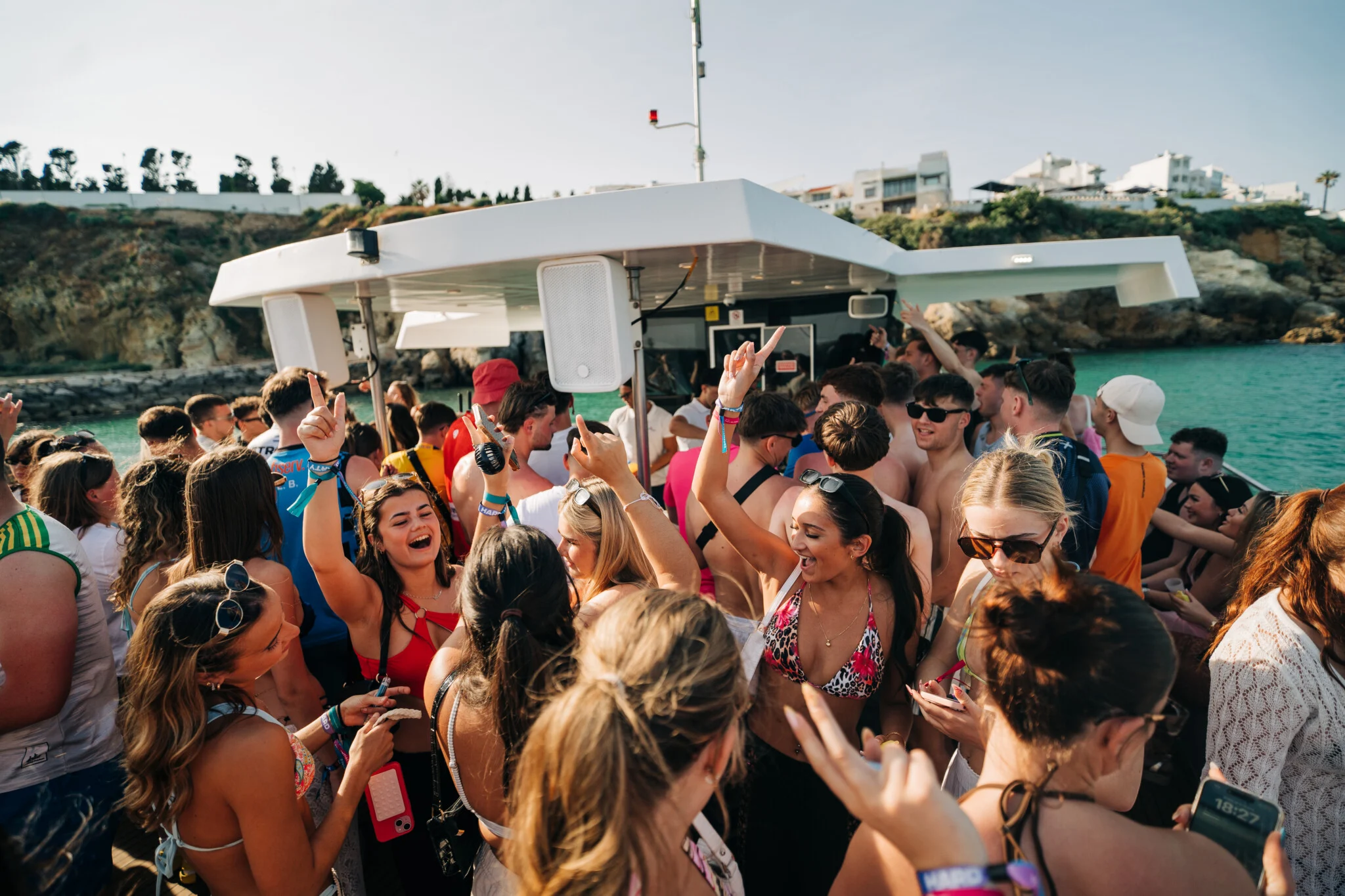 Girls and lads partying on deck at the Albufeira Boat Party in Albufeira, dancing and enjoying drinks under the sun with stunning coastline views.