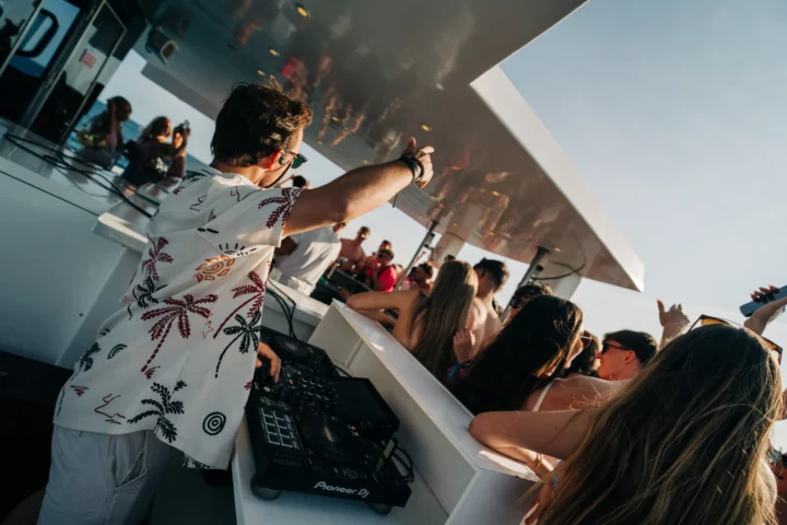 DJ playing live on deck as lads and girls dance under the sun at the Albufeira Boat Party enjoying music, cocktails, and Algarve sea views.