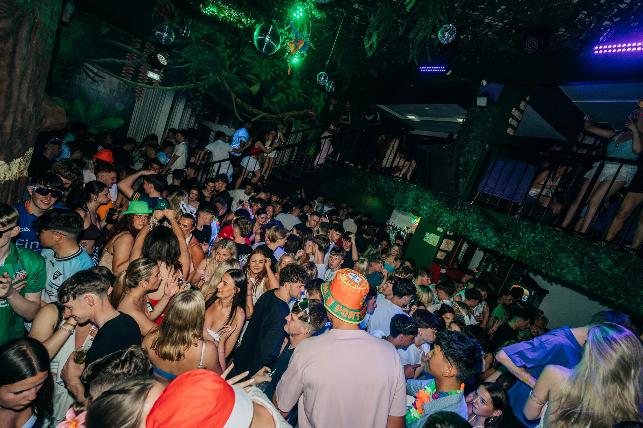 Packed dancefloor at Club Tropicana Albufeira as partygoers celebrate under neon lights and jungle-themed décor.