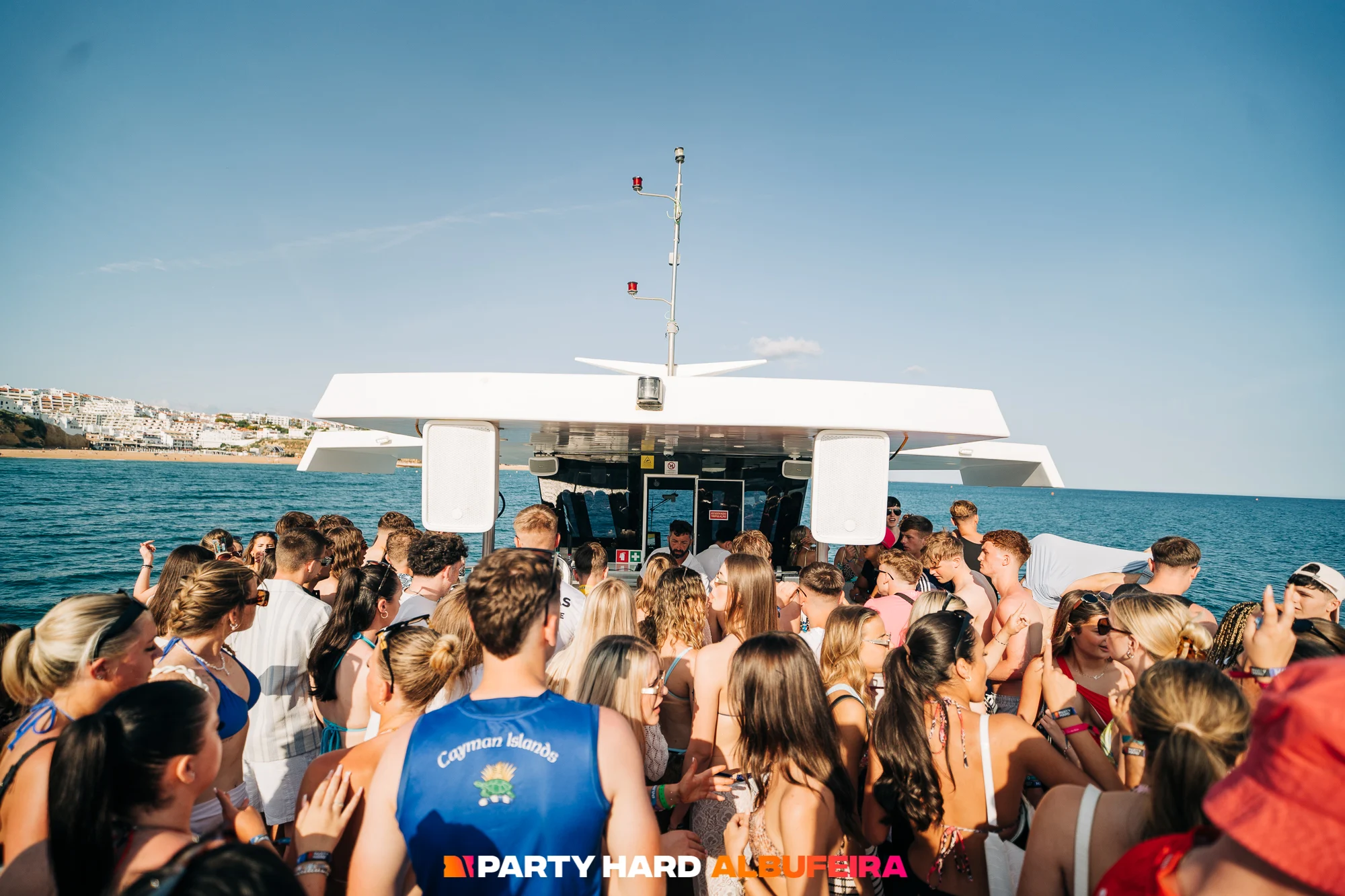 Crowd of lads and girls dancing on deck with a DJ at the Albufeira Boat Party, enjoying music, sunshine, and views of the Algarve coastline.