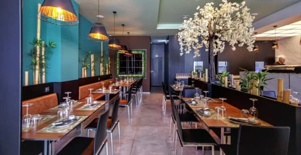 Stylish interior of Prime Sushi & Cocktail Bar in Albufeira, featuring modern tables, bamboo decor, and a cherry blossom tree.