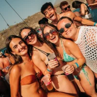 Girls smiling on a Tenerife boat party, drinks in hand, sun blazing, music pumping and full daytime party energy