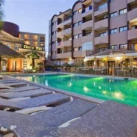 Evening view of Choromar Apartments in Albufeira featuring a lit outdoor swimming pool, sun loungers, and surrounding balconies.