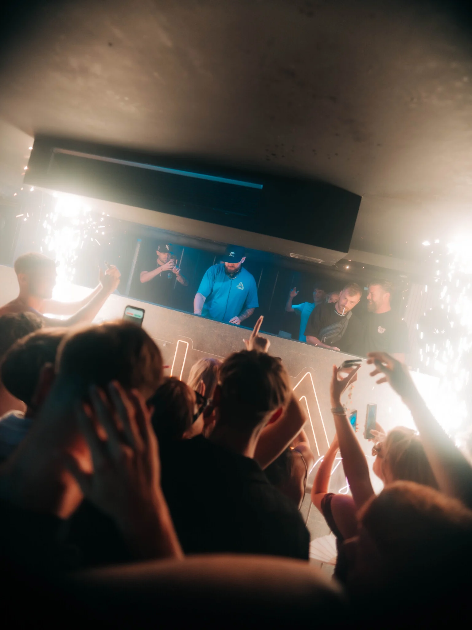 Ayia Napa Abode event with DJs performing on stage as the crowd dances under sparklers and neon lights in the nightclub