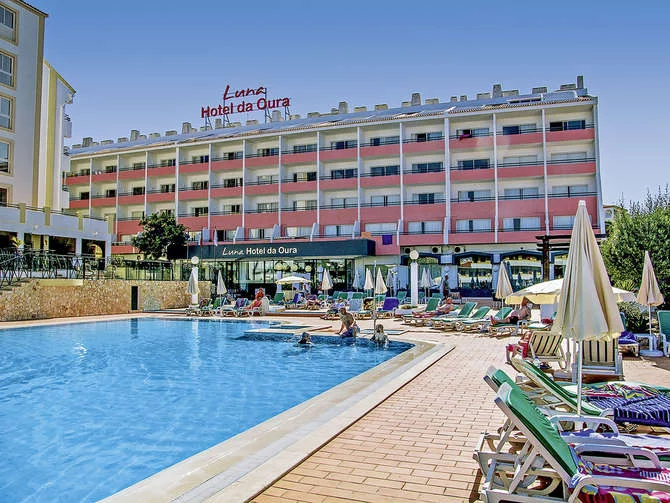 View of Luna Hotel da Oura in Albufeira with outdoor pool, sun loungers, and guests relaxing under clear blue skies.