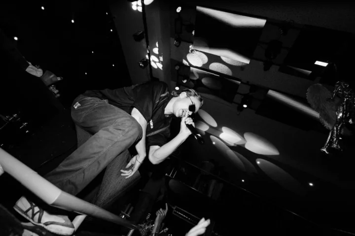 Performer on stage at Club Heaven Albufeira hyping up the crowd under bright lights and big party energy.