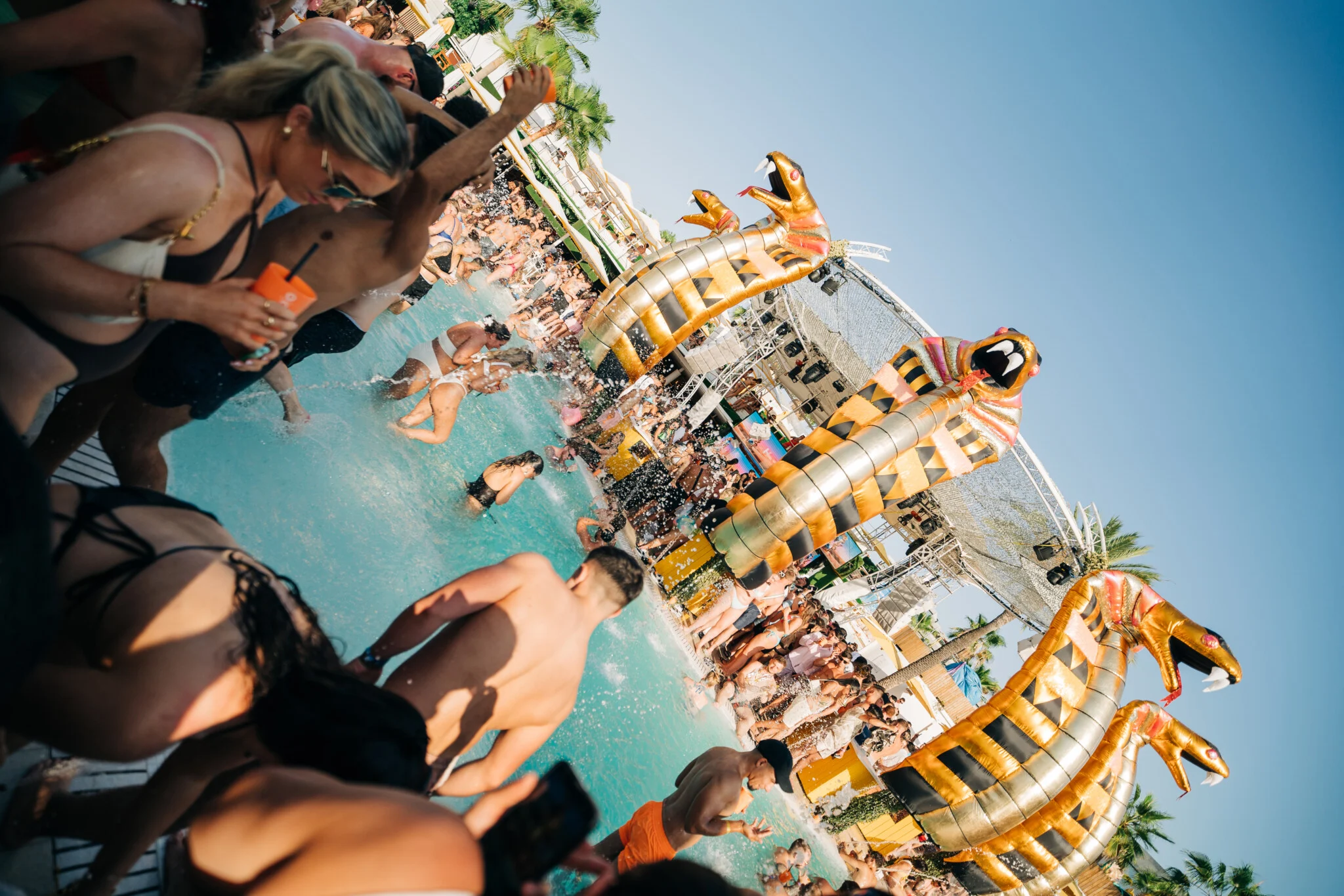 Crowds partying in the pool at Ibiza’s hottest beach club, golden cobra decor, music pumping and drinks flowing.