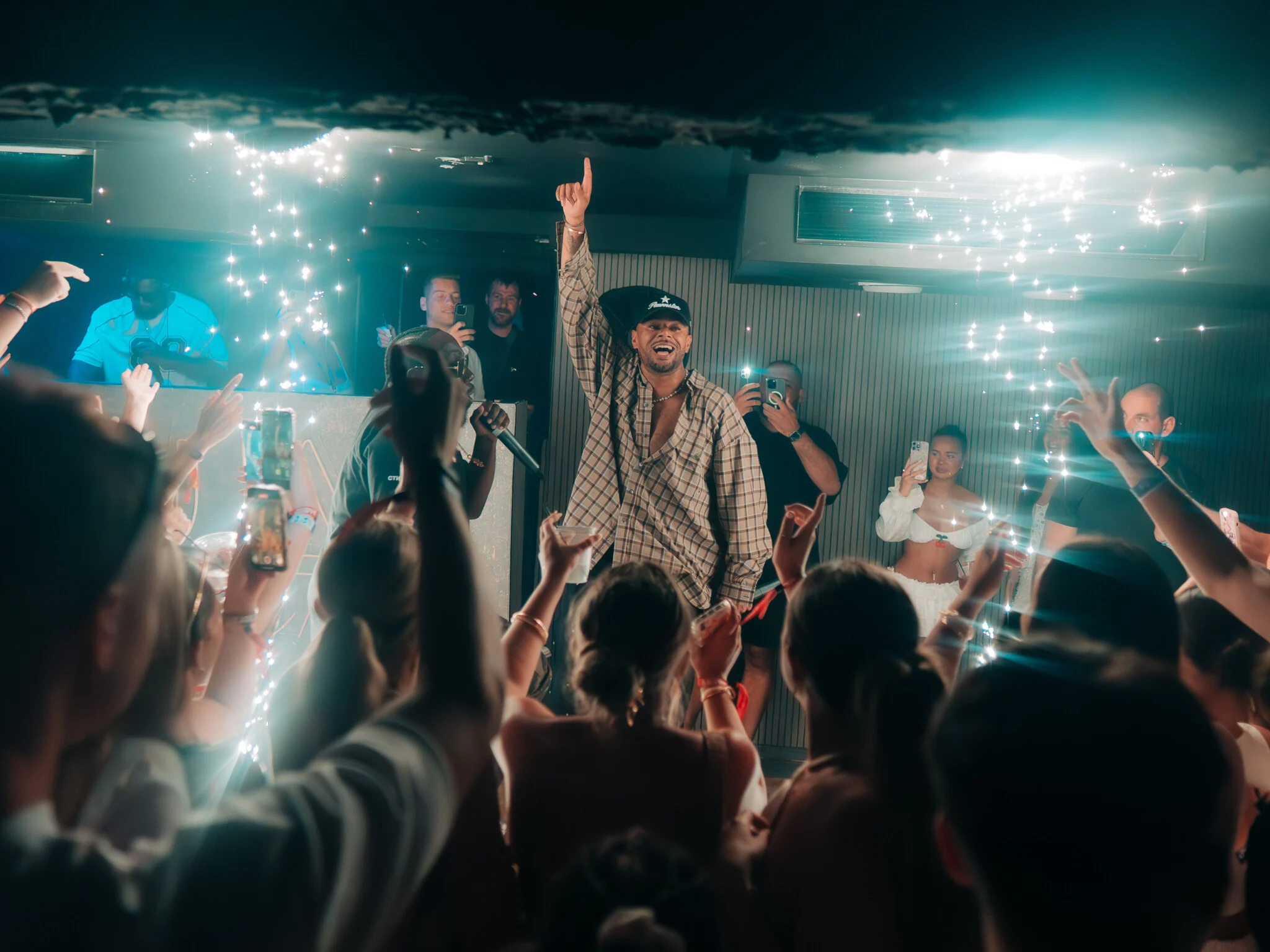 Crowd partying at Ayia Napa event with live performer on stage and sparklers lighting up the nightclub atmosphere