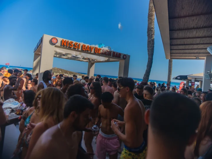Partygoers at Nissi Bay Beach Bar in Ayia Napa enjoying a lively daytime beach party with music and drinks by the sea