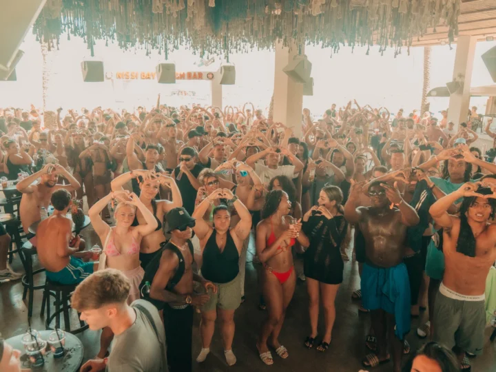 Crowds at Nissi Beach Party in Ayia Napa making heart signs and enjoying the daytime beach bar atmosphere