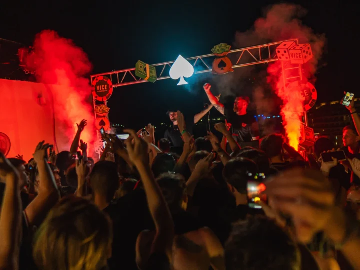 Crowd partying at Ayia Napa Vice rooftop event with DJs, red smoke effects and neon stage lights at night