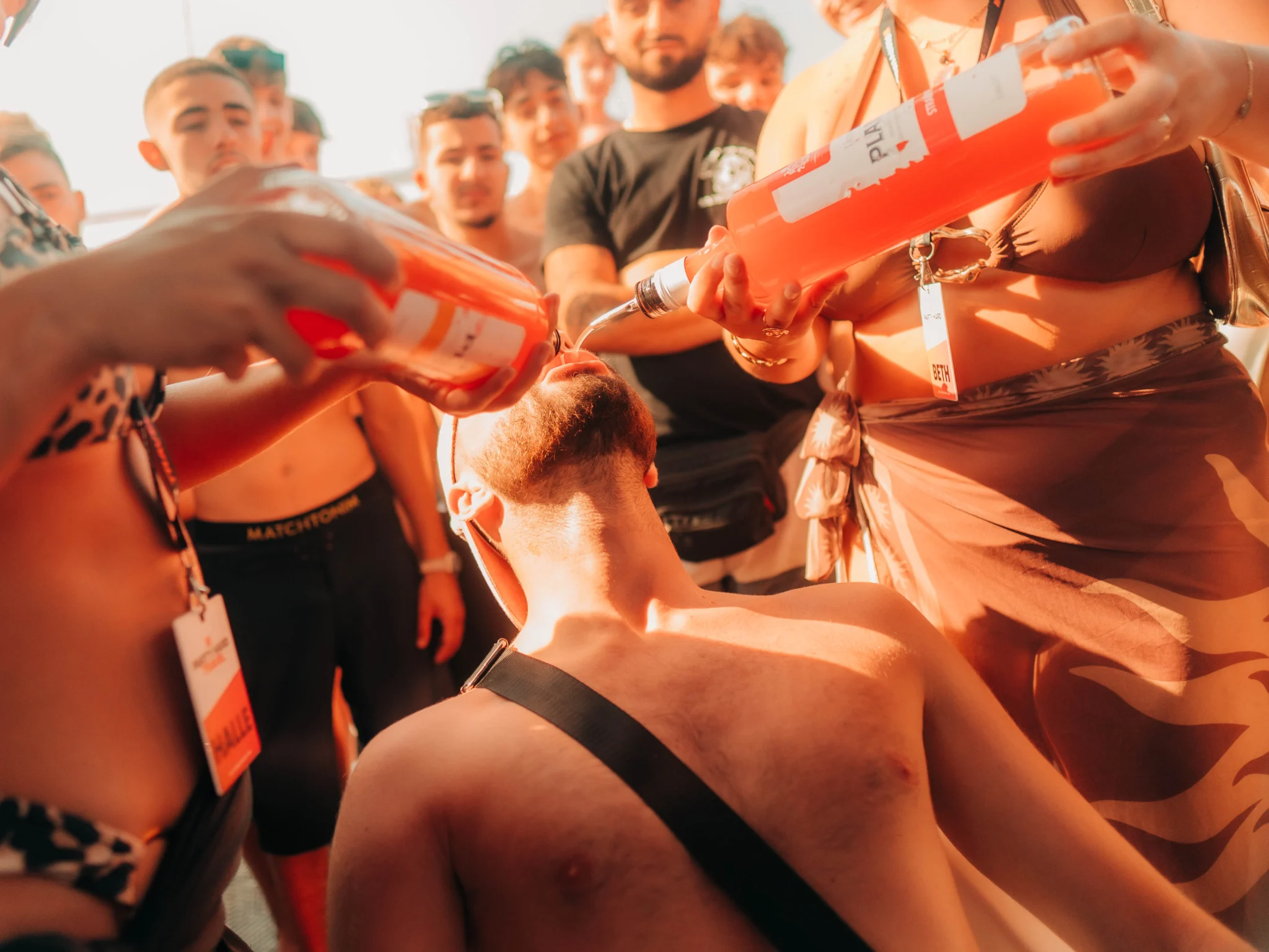 Partygoers at an Ayia Napa boat party pouring drinks and celebrating together under the sun