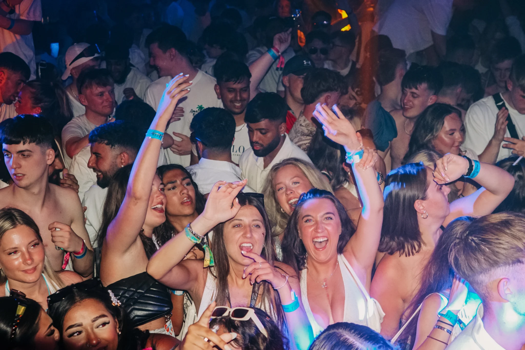 Lads and girls packed into a Barcelona club, arms up and shouting as the room erupts with full-on party energy.