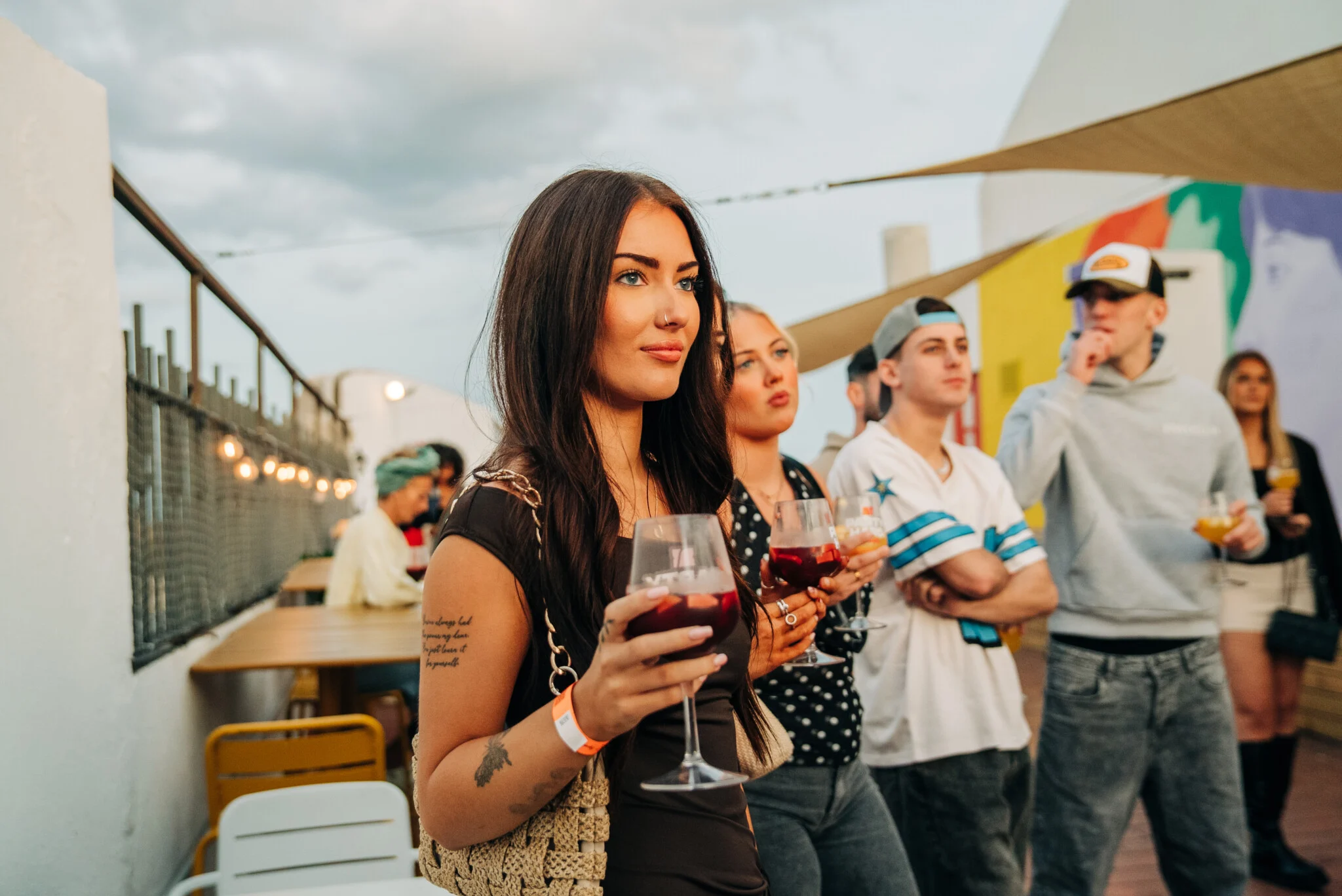 Lads and girls at a Barcelona rooftop pre-party, drinks in hand and sunset vibes rolling before the night kicks off.