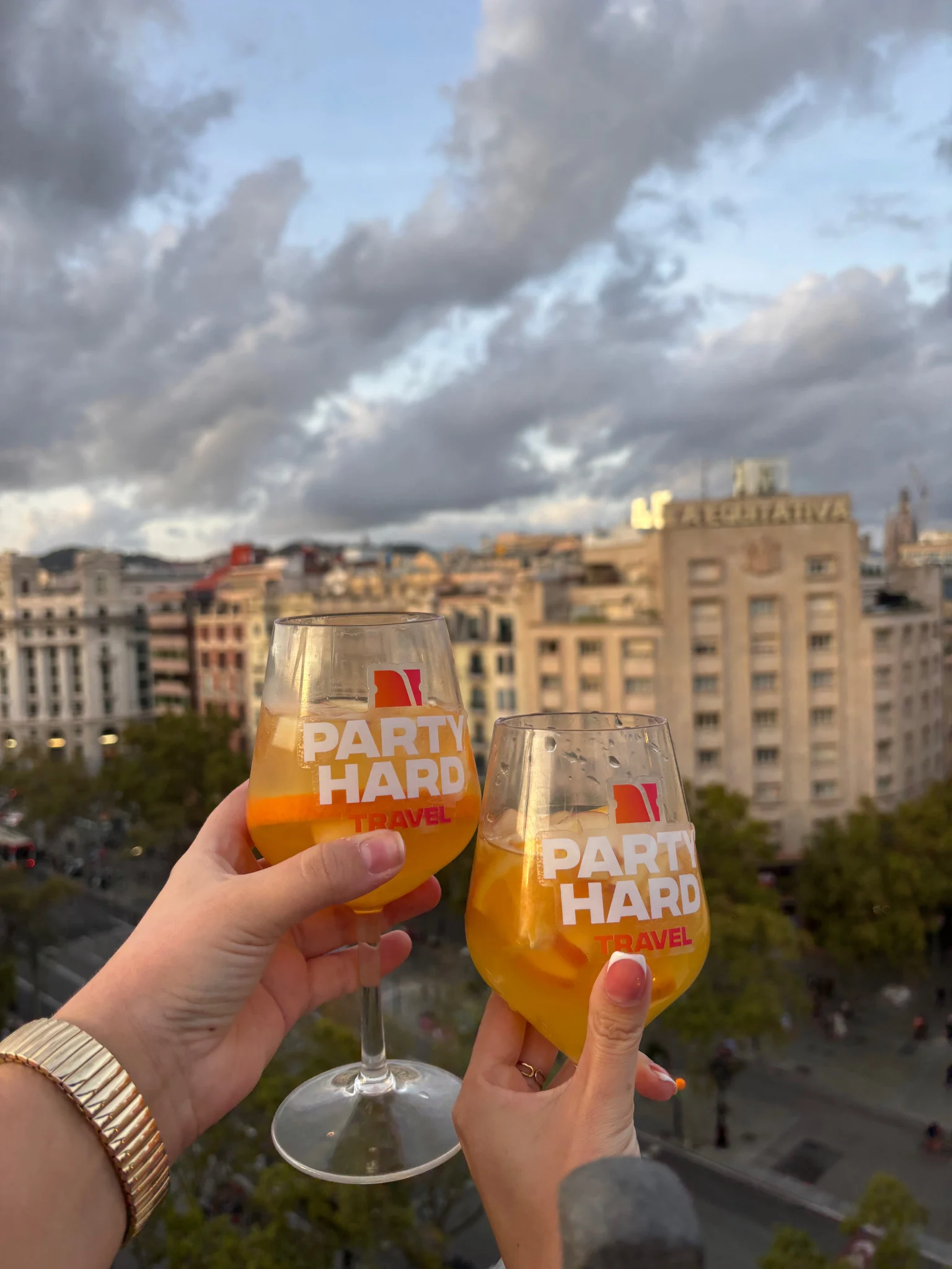 Two glasses of Party Hard sangria raised over Barcelona’s skyline, kicking off the evening with proper holiday drinks vibes.