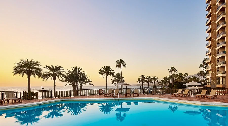 Sol Tenerife Hotel pool at sunset, palm-lined terrace and sea views setting the scene for pre-party drinks and warm nights