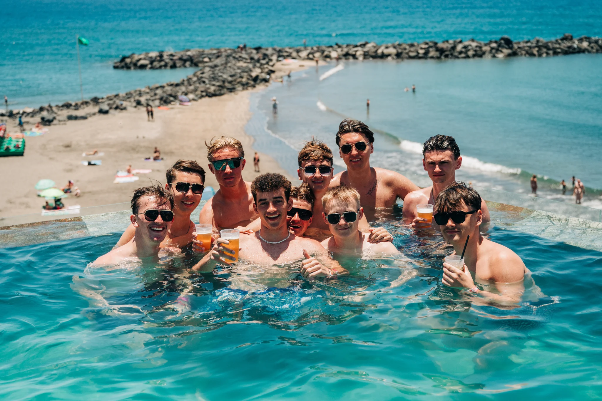 Group of lads posing together in a pool overlooking the Tenerife coast