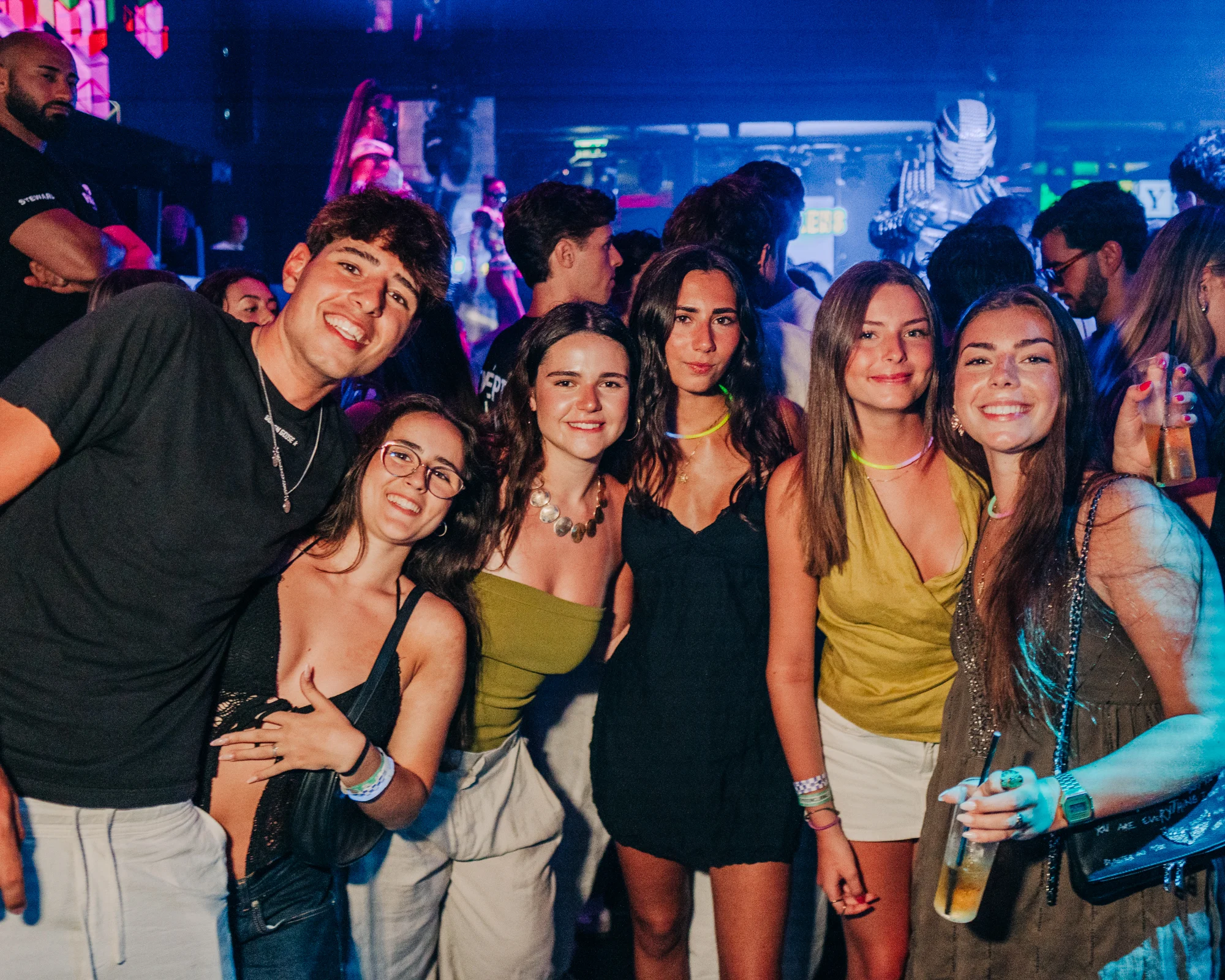 Group of lads and girls posing together under club lighting in Malta